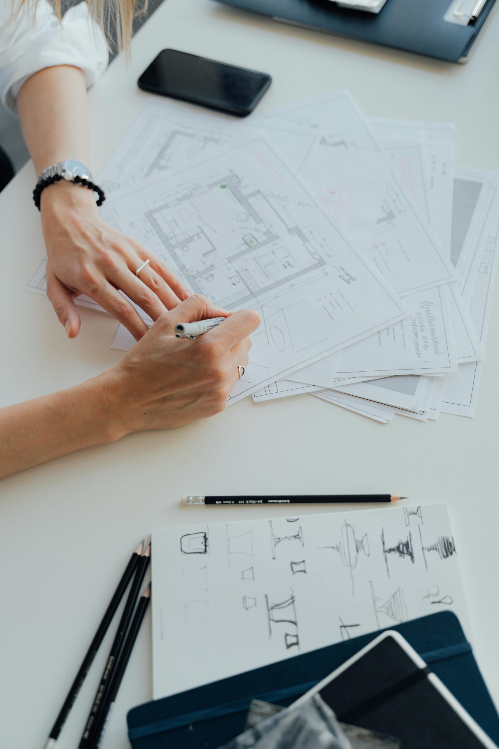 Home Hands of an architect drafting floor plans, surrounded by drawing tools and documents.